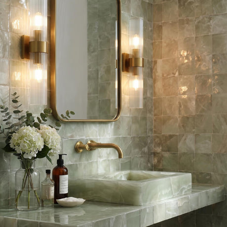 A contemporary bathroom featuring two Barclay 2 Light Wall Sconce 20" in Modern Brass with ribbed glass shades flanking a mirror above a green tile vanity.