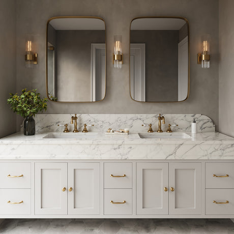 Three Barclay 13" tall Wall Sconces in Brass with clear fluted glass above a double vanity with two modern brass mirrors