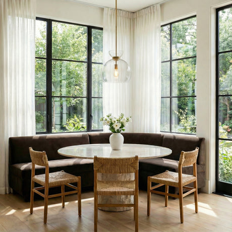 Matilda Medium Pendant 16, Modern Brass and Clear Glass, styled in a Modern Dining Room with wood floors and large windows.