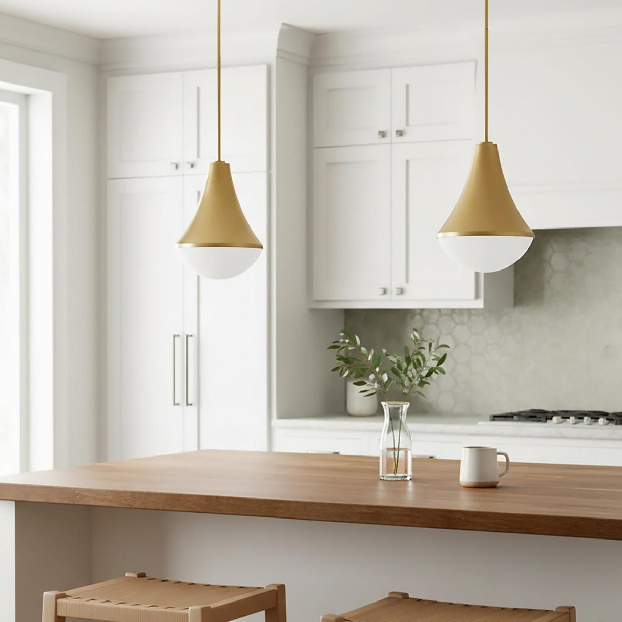 A transitional kitchen features two Skylar Pendant 11", Satin Brass pendants in satin brass and frosted glass over a wood island with white cabinets and hexagon tile backsplash.