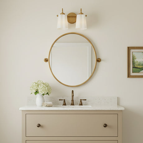 Connie 2 Light Vanity, Rustic Brass with Opal Glass - A bathroom vanity featuring a brass two-light fixture with opal glass shades mounted above a round brass mirror.