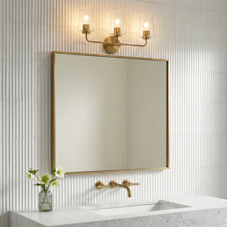 Wyatt 3 Light Vanity, Legacy Brass with Clear Glass geometric vanity in a Contemporary Bathroom with a fluted tile wall and marble vanity.