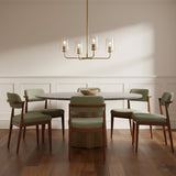 Wyatt 4 Light Chandelier 25 - A modern dining room with a satin brass chandelier, a gray oval table, and sage green chairs.