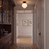 A transitional foyer features an Irving Medium Flush Mount 12", Black with a white glass shade set above dark wood cabinetry and light hardwood floors.