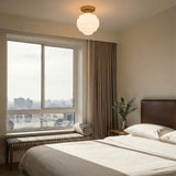 Irving Medium Flush Mount 12", Satin Brass scalloped flush mount in a Modern Bedroom with a brown leather headboard and patterned bench.