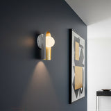 Kassidy Wall Sconce 10 - White and Satin Brass wall sconce with a modern design against a dark gray wall, illuminated by a warm glow.