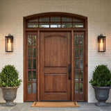 A transitional home entry featuring matte black Sinclair Outdoor Wall Light lanterns flanking a stained wood door on white brick at twilight with boxwood urns.