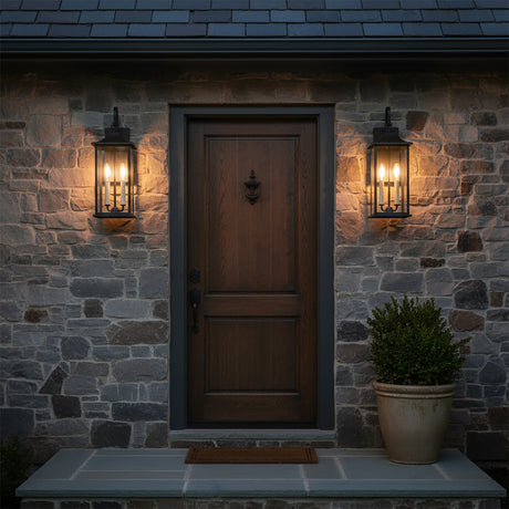 Lorraine Outdoor Wall Light, Medium 21" Black - Two black lanterns flanking a dark wood door on a stone wall