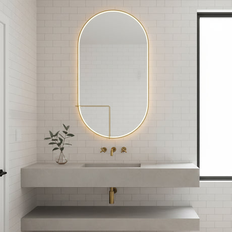 Chadwick Large LED Oval Mirror 24" x 42", Brushed Brass - An oval LED mirror in a bathroom setting with a floating vanity and white subway tile.