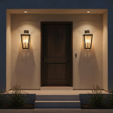 Barrett Outdoor Wall Light, Large 26" Textured Black - Two black outdoor wall lights illuminate a dark wooden door and the surrounding textured wall.