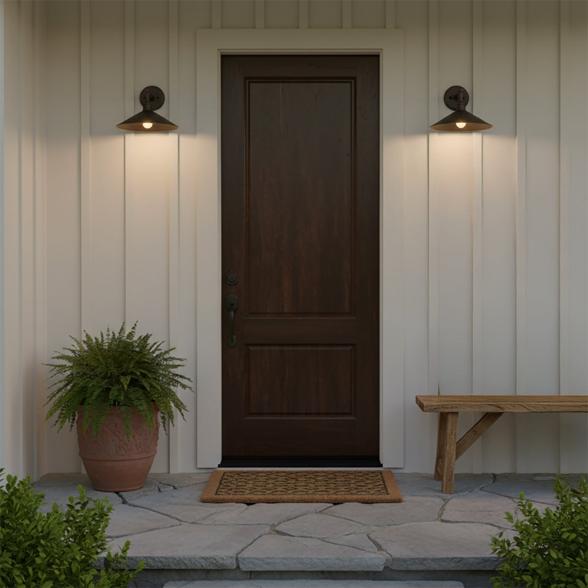 Artie Outdoor Wall Light, Medium Antique Bronze - Two antique bronze wall lights flank a dark wood door with a potted fern and a wooden bench.