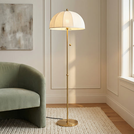 Mayfair Floor Lamp, Aged Brass styled in a Transitional Living Room with paneled walls and a textured rug.