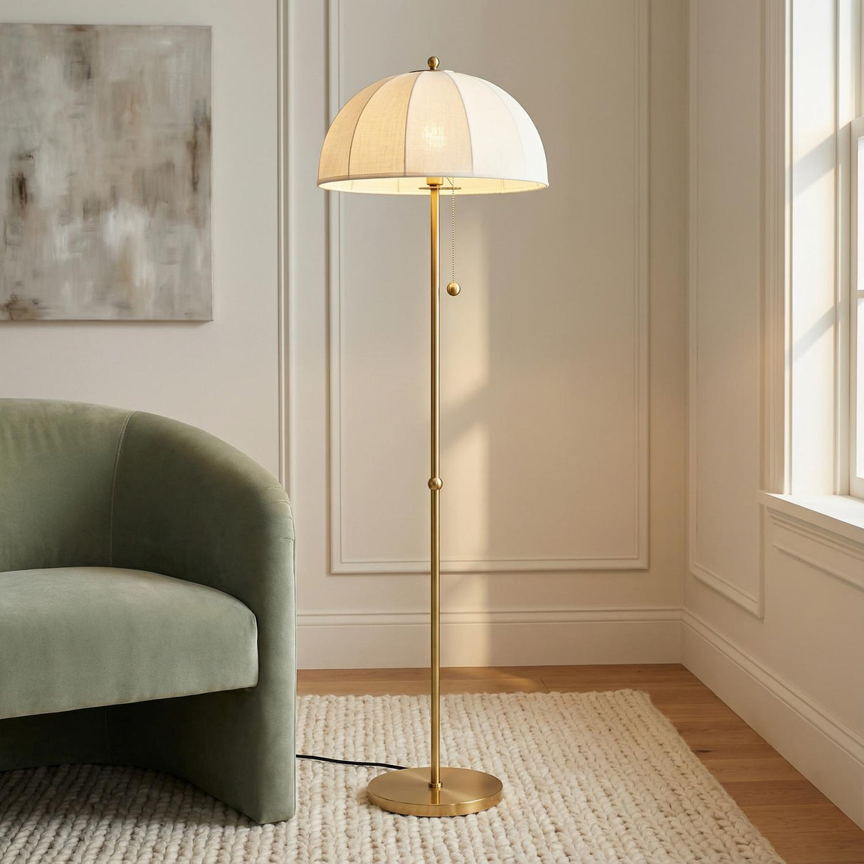 Mayfair Floor Lamp, Aged Brass styled in a Transitional Living Room with paneled walls and a textured rug.