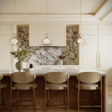Modern luxe kitchen with three Rhett 12" Pendant lights in aged brass and glass hung above a large kitchen island