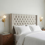 Rhett Wall Sconce 17", Aged Brass globe Wall Sconce in a Transitional Bedroom with a tufted headboard and walnut nightstand.