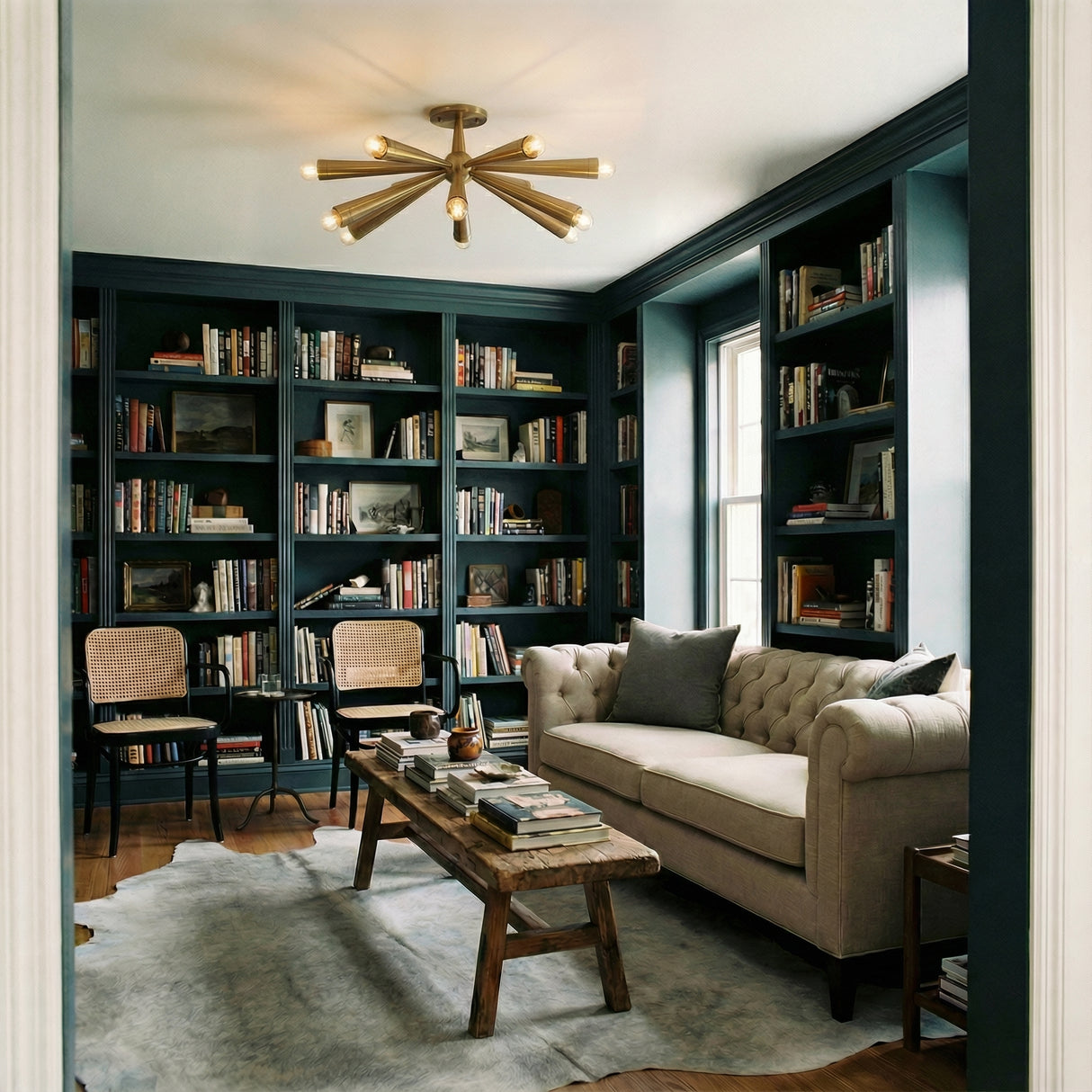 Patina Brass geometric semi-flush mount in a Transitional Living Room with dark built-in bookshelves and tufted sofa.