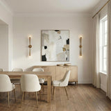 Camellia 2 Light Wall Sconce 34", Patina Brass linear wall sconce in a Contemporary Dining Room with an oak table and abstract art.