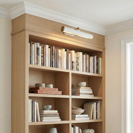 Judy Medium Picture Light 16", Aged Brass and White linear picture light in a Transitional Office with a light oak bookshelf.