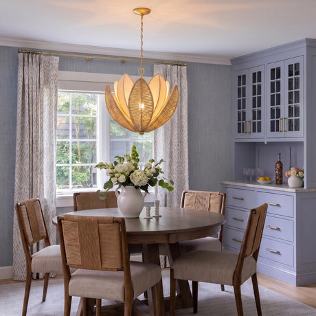 A coastal dining room with the Gardenia Chandelier 24 inch Gold Leaf and Natural Beads hanging over a round wood table beside blue cabinetry.