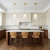 Cora Pendant, Brass linear pendant in a Transitional Kitchen with a white marble island and tan leather stools.