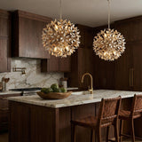 Distressed gold off-white leaf design Chandelier in a Transitional Kitchen with a marble island & woven leather stools.