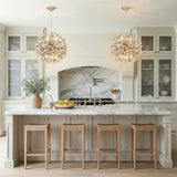 Weathered Gold leaf design pendant in a Transitional Kitchen with a white marble island & natural wood stools.