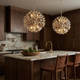 Distressed gold off-white leaf design Chandelier in a Transitional Kitchen with a marble island & woven leather stools.
