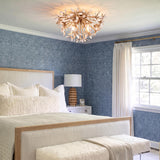 A coastal bedroom features the Genevieve Semi-Flush 20", Natural Rope and Coco Shells fixture on the ceiling above a wood bed framed by blue patterned wallpaper.