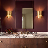 A contemporary bathroom with burgundy walls featuring two Barron Wall Sconce 9-inch Textured Gold Leaf fixtures flanking a mirror above a veined marble countertop.
