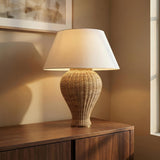 Natural Wicker woven table lamp with a white shade and aged brass accent in a Modern Living Room with a dark wood credenza.