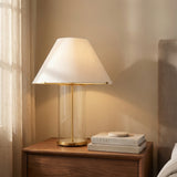 Elena Table Lamp, Aged Brass and Clear Glass linear Table Lamp in a Transitional Bedroom with a dark wood nightstand and fabric headboard.