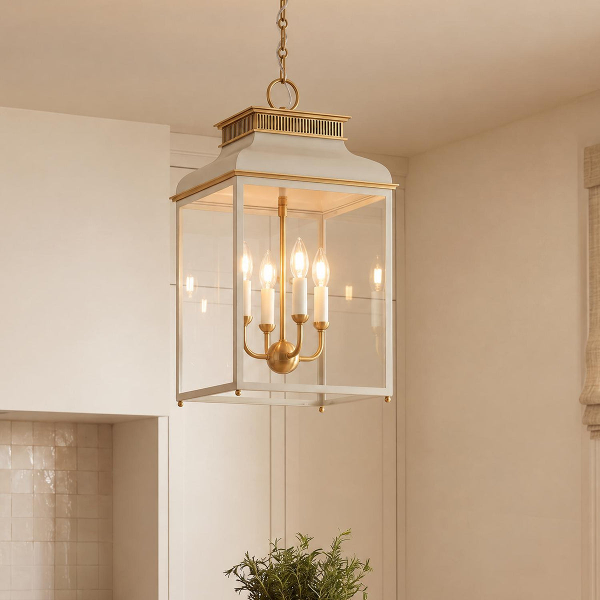 A transitional kitchen features the Harriet Lantern Pendant 13", Off White and Aged Brass hanging above an island, framed by cream cabinetry and glazed tile backsplash.