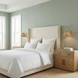 Karina Wall Sconce 8", Woven Wicker and Aged Brass woven wall sconce in a Transitional Bedroom with a white upholstered bed.