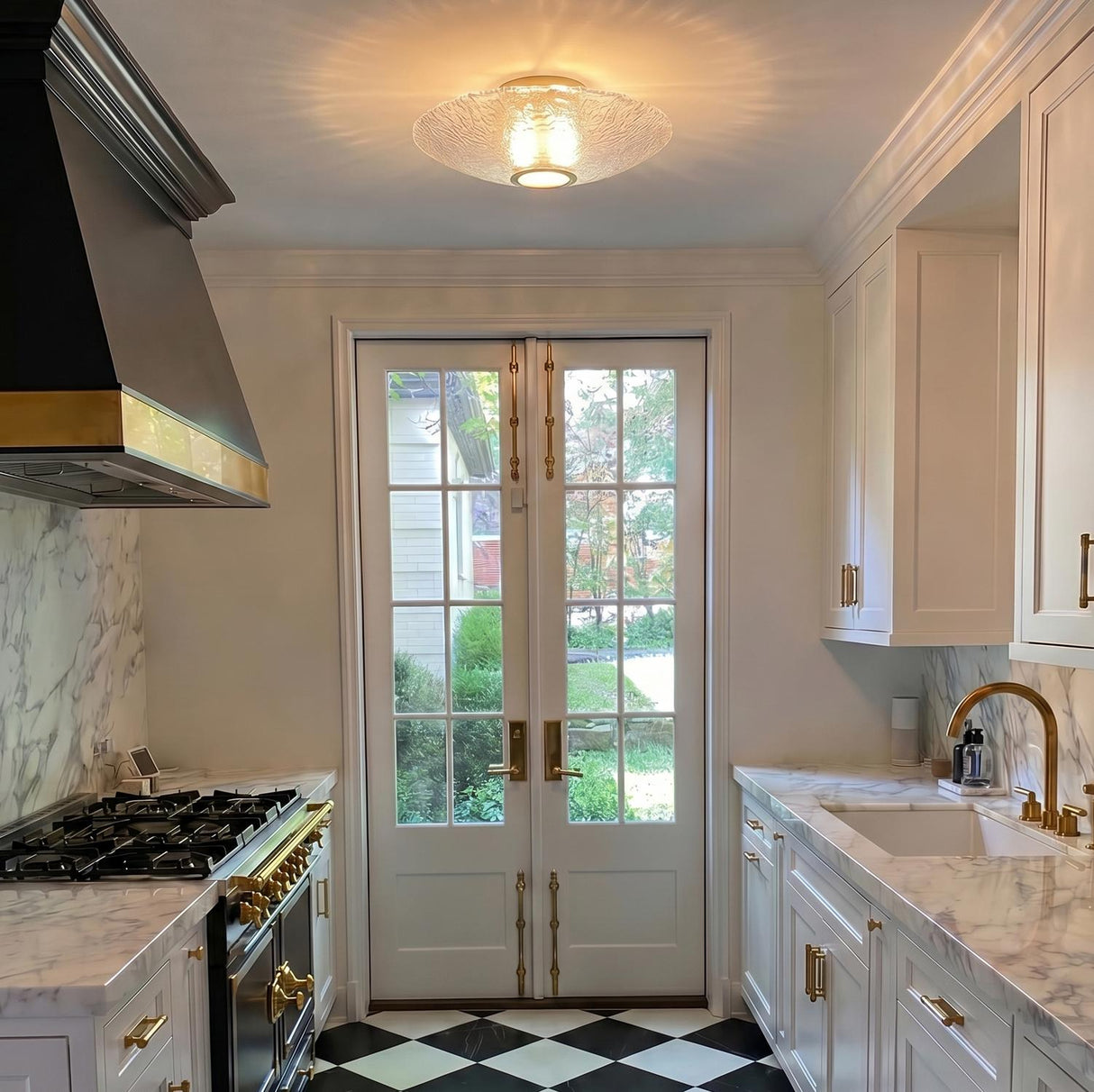 A transitional kitchen with an aged brass and piastra glass flush mount installed along the ceiling center between marble counters and black and white checkered tile.