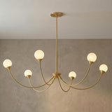 Isabella 6 Light Aged Brass globe design Chandelier in a Contemporary Dining Room with a textured plaster wall.