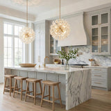 Aged Brass globe pendant with faceted crystals in a Contemporary Kitchen with a white marble island and wood stools.