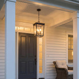 Radcliffe Outdoor Hanging Light 12", Old Bronze geometric Outdoor Hanging in a Colonial Outdoor with a wicker chair and dark door.