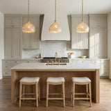 A transitional kitchen with three Valentina Medium Pendant 14", Soft Brass and Capiz Shell fixtures over a fluted wood island with white marble and taupe cabinets.