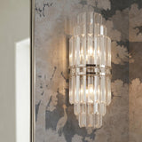 A traditional foyer with a Maxwell Large Wall Sconce 20" in crystal and polished nickel mounted on scenic tree-patterned mural wallpaper beside a mirror.