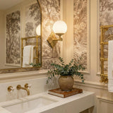 Victoria Wall Sconce 12", Aged Brass and Opal Ribbed Glass globe wall sconce in a Traditional Bathroom with toile wallpaper and marble vanity.