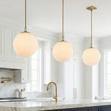 Victoria Pendant, Aged Brass and Opal Ribbed Glass globe pendant in a Transitional Kitchen with a white marble island.