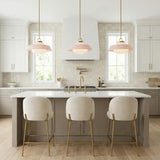 A transitional kitchen features three Blaine Medium Pendants 16 inch Brass and Rose Quartz suspended over a white quartz island with cream stools and tiled backsplash.