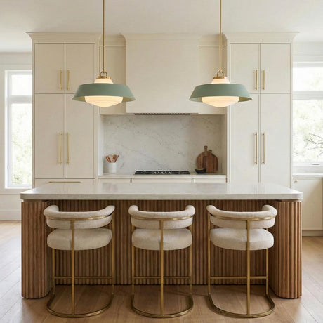 A contemporary kitchen features two Blaine Large Pendant 20", Brass and Sage Green with brushed brass hardware over a fluted wood island and marble backsplash.