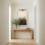 Spencer LED Picture Light 20", Brass with Brown Leather Accents linear Wall Sconce in a Transitional Hallway with an oak console table.