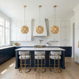 A transitional kitchen featuring three Florence Pendant 13", Soft Brass pendants over a white marble island with navy cabinets and gold-framed bar stools.