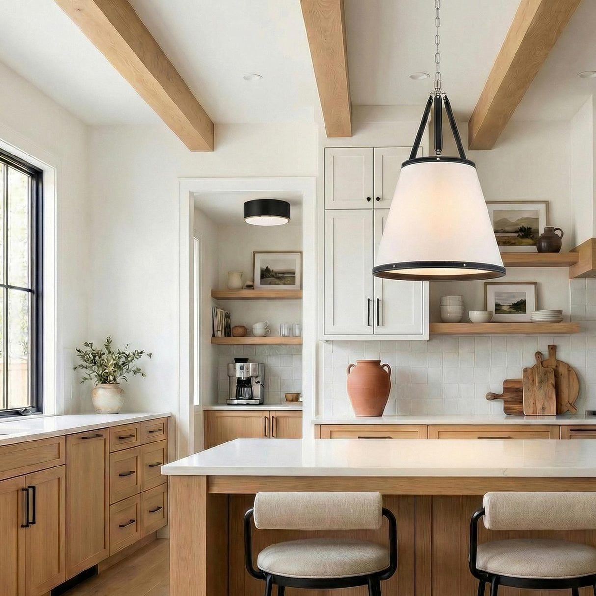 A transitional kitchen features a Spencer Large Pendant 21-inch, Polished Nickel with Black Leather Accents over a white quartz island with natural wood cabinets and exposed ceiling beams.