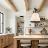 A transitional kitchen features a Spencer Large Pendant 21-inch, Polished Nickel with Black Leather Accents over a white quartz island with natural wood cabinets and exposed ceiling beams.