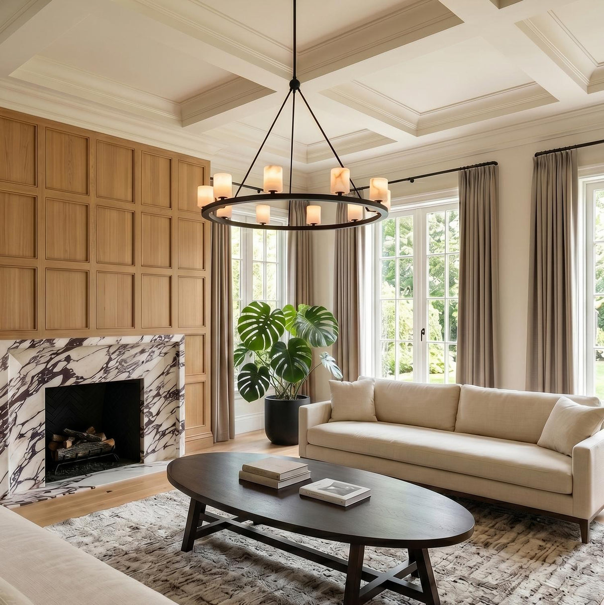 A transitional living room with the Arlo 10 Light Ring Chandelier 35", Matte Black and Alabaster, suspended from a white coffered ceiling near a marble fireplace.