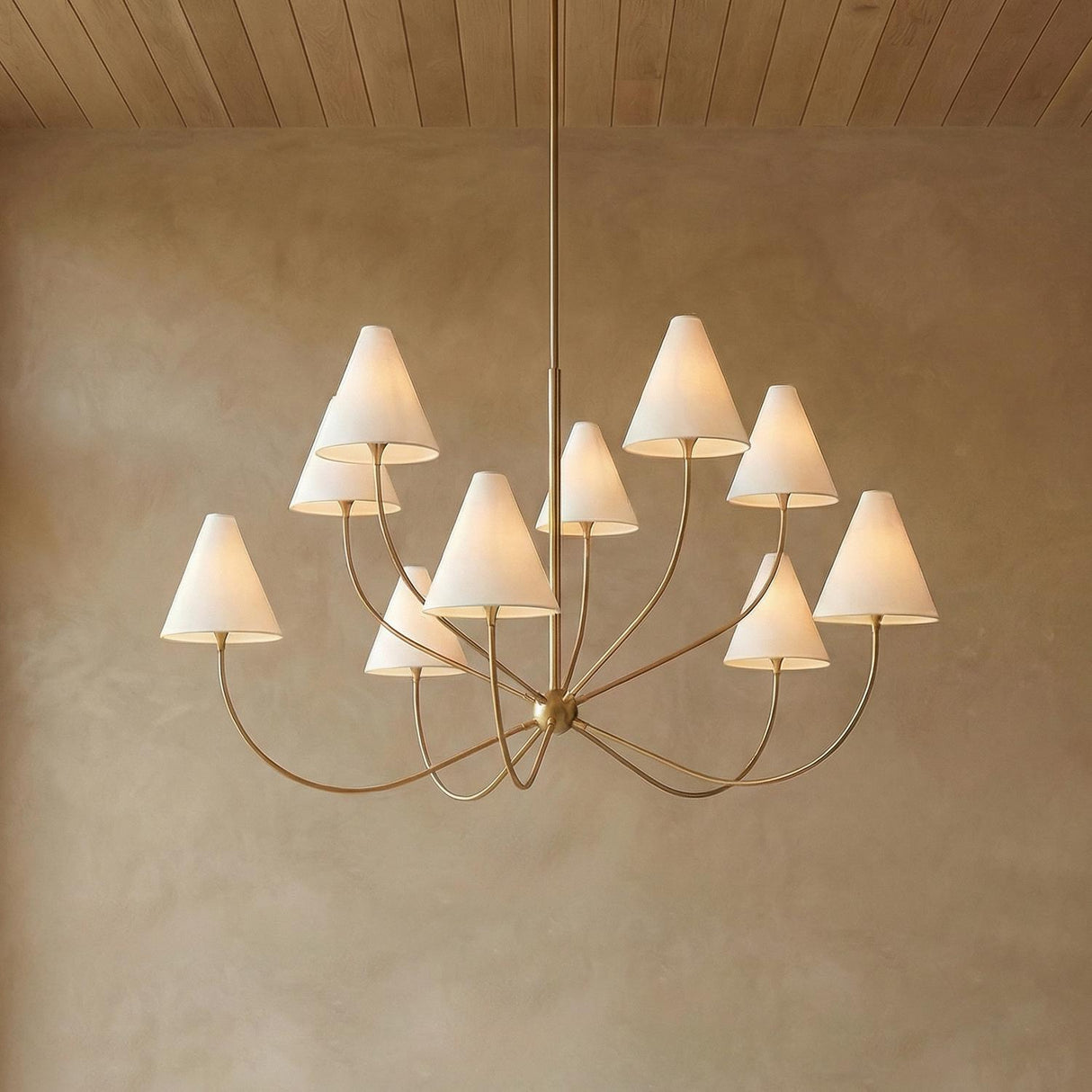 Yara 10 Light Chandelier 60", Patina Brass geometric chandelier in a Mediterranean Living Room with plaster walls and wood ceiling.