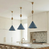 A contemporary kitchen featuring three Hadley Pull-Down Pendant 18", Vintage Blue and Patina Brass fixtures hanging over a terrazzo island and a mosaic tile backsplash.